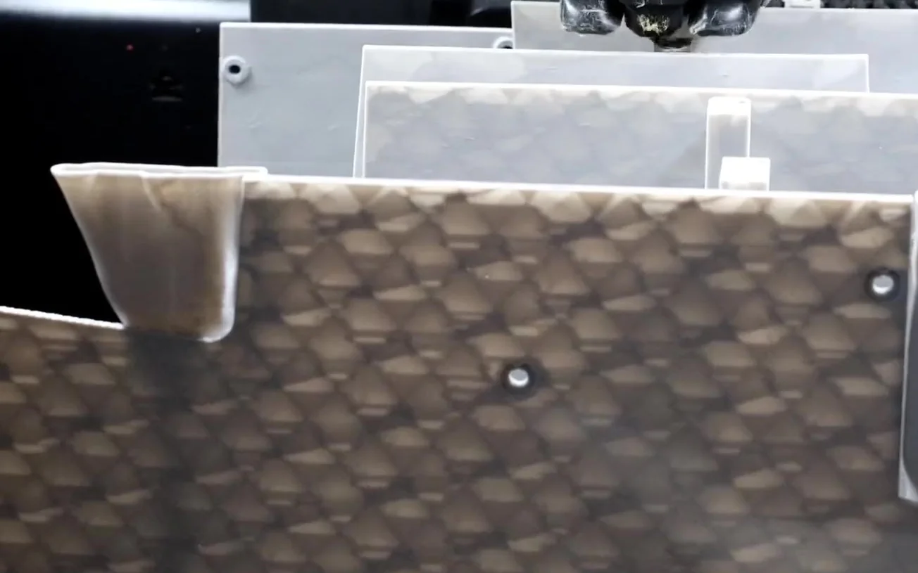 Flat printed panels standing on edge inside a Bambu Lab 3D printer mid-job, with the toolhead above them