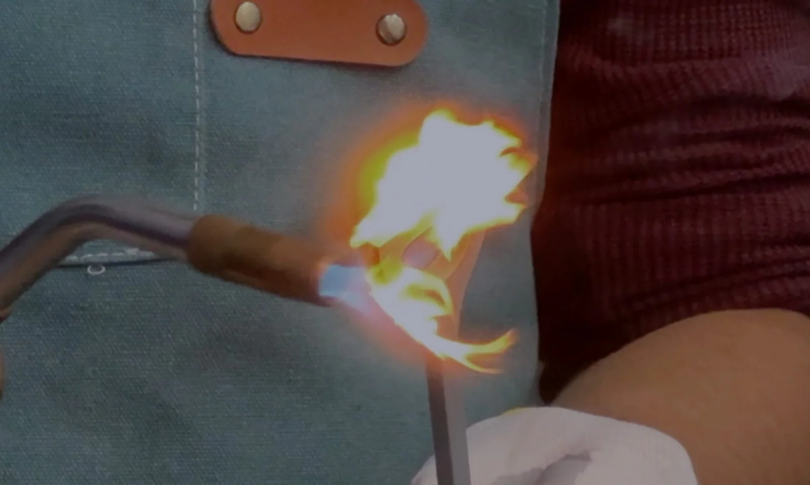 A blowtorch flame applied to a 3D-printed plastic test strip during a flame-retardant burn test