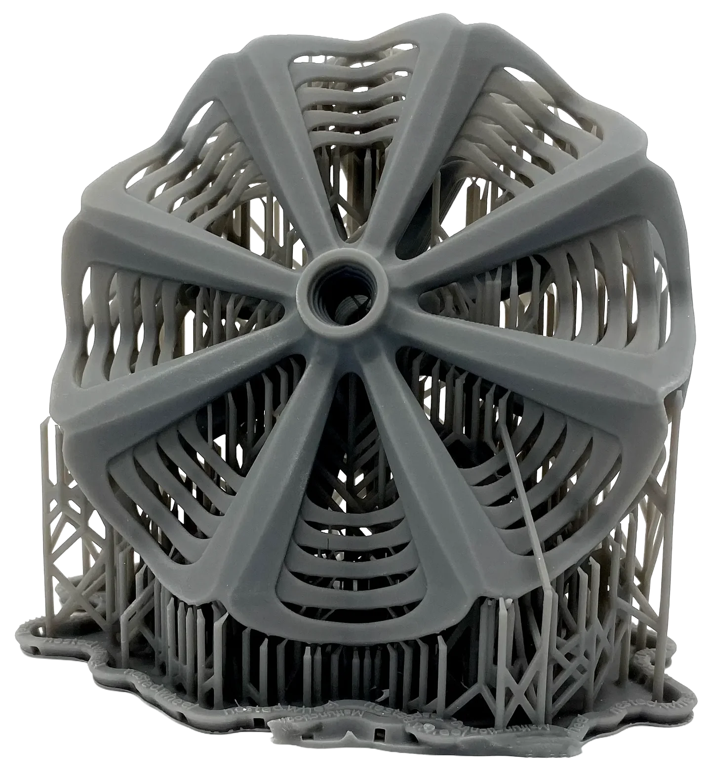 A 3D-printed spoked wheel still attached to its lattice support raft, showing the fine detail the process produces